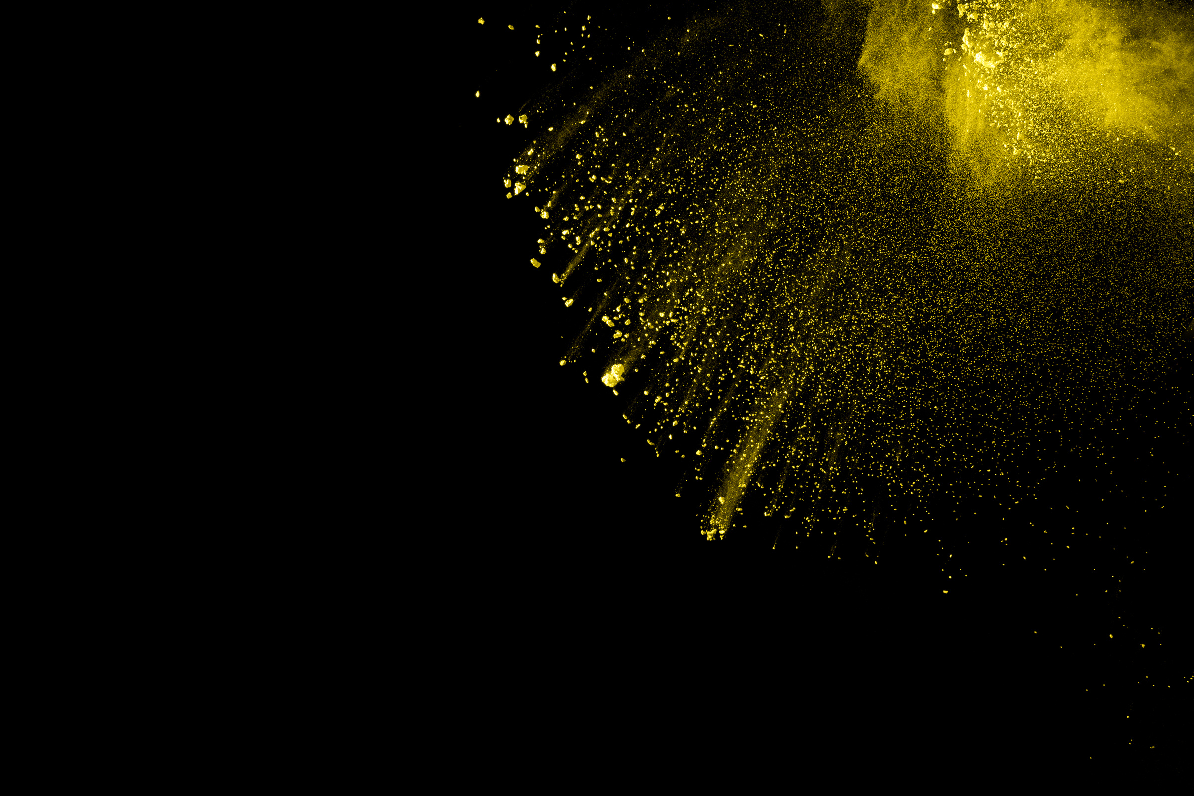 Yellow dust particles explosion on black background.Yellow powder  splash.